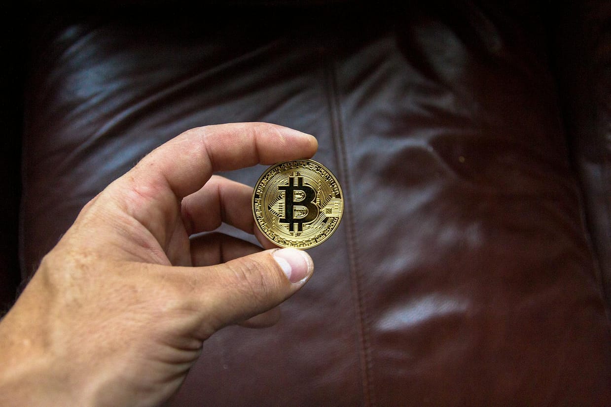 round gold colored and black coin on person s hand